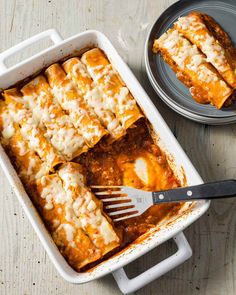 a casserole dish filled with lasagna and cheese next to a fork