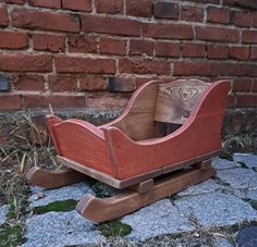 a wooden toy sled sitting on the ground next to a brick wall