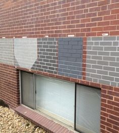 the side of a brick building with several different shades of gray and white paint on it