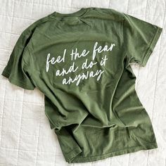 Feel the Fear and Do it Anyway. ✨ I'm a big believer in doing things before you're ready. Nothing great ever happens when you're in your comfort zone. You never know unless you try! Whether it's life, motherhood, business ... you just have to go for it. 100% cotton Comfort Colors tee that gets softer with every wash. Tone on tone embroidery on front; printed on back. Available for a limited time. - Comfort Colors Tee - Medium Weight - Gets softer with every wash - Size up for a stylish oversized Relaxed Fit Short Sleeve Shirt With Lettering, Green Cotton Slogan Shirt, Green Cotton Shirt With Slogan, Green Top With Lettering And Relaxed Fit, Green Cotton T-shirt With Lettering, Green Top With Lettering In Relaxed Fit, Green Relaxed Fit Top With Lettering, Do It Anyway, Embroidered Shorts