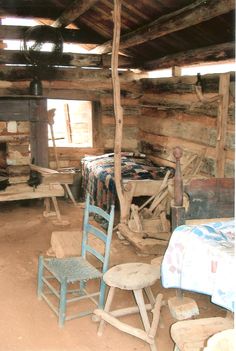 an old cabin with two chairs and a bed