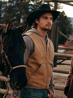 a man wearing a cowboy hat standing next to a horse