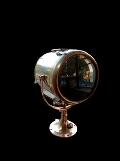 a mirror sitting on top of a metal stand in front of a black background with the reflection of a train