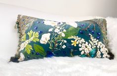 a blue pillow with white flowers and green leaves