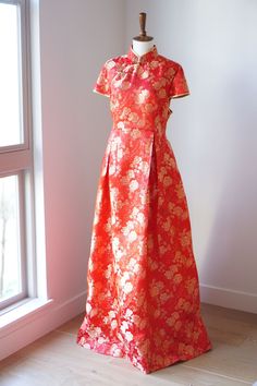 an orange and pink dress on a mannequin in front of a white wall