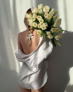 a woman with flowers in her hair standing against a wall