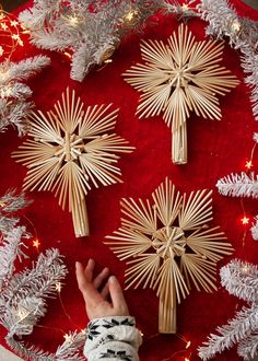 a person reaching for wooden crosses on top of a red table cloth with christmas decorations around it