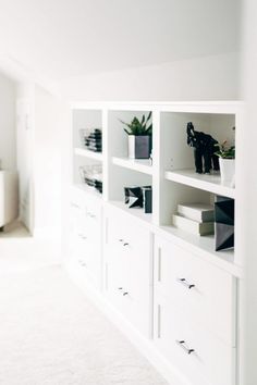 a white bookcase filled with lots of books next to a wall mounted planter