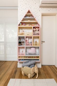 a pink shelf with stuffed animals and toys on it in the corner of a room