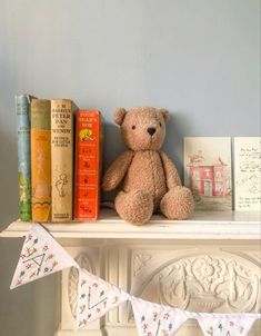 a teddy bear sitting on top of a mantle next to books