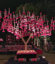 a tree decorated with pink flowers and hanging lights in the middle of a banquet hall