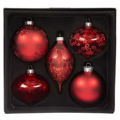 four red christmas ornaments in a black box