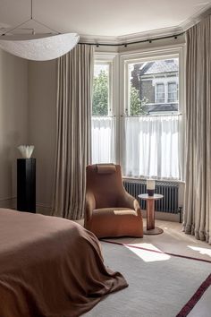 a bedroom with a bed, chair and large window in it's center area