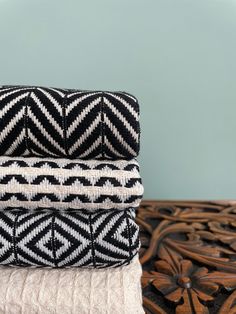 three black and white blankets stacked on top of each other in front of a blue wall