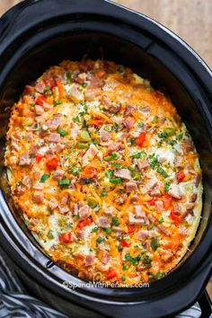 an open crock pot filled with ham and cheese casserole on top of a wooden table