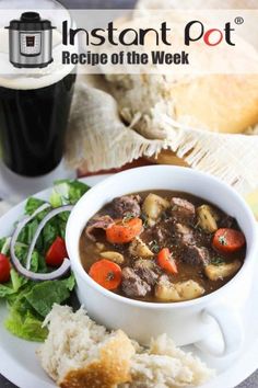 a white plate topped with a bowl of beef stew and veggies next to bread