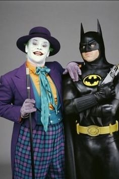 two actors dressed up as batman and joker in front of a wooden frame with autographed characters