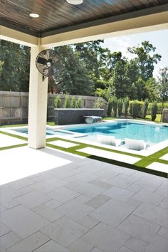 an outdoor swimming pool with tiled floors and white walls, surrounded by greenery in the background