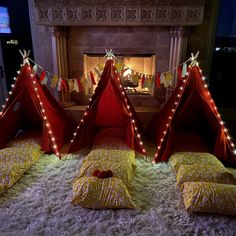 three teepees are set up in front of a fireplace with lights on them