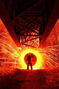 a man holding an umbrella standing in the middle of a tunnel filled with bright sparks