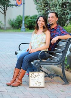 a man and woman sitting on a bench with a sign that says god is for you