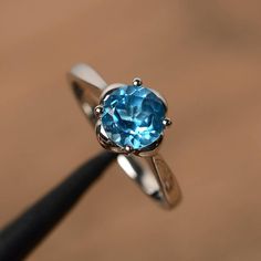 It is a real Swiss blue topaz  ring, round cut, measures 7mm*7mm, weight about 1.68 cts. The basic metal is sterling silver and plated with rhodium.To change the metal to a solid gold (white/rose) or platinum is also available, please ask for a quotation if you want.You can also go to my shop Home for more elegant rings: https://www.etsy.com/shop/godjewelry?ref=hdr_shop_menuSwiss blue topaz is birthstone of NovemberMore Swiss blue topaz rings:https://www.etsy.com/shop/godjewelry?ref=seller-platf Topaz Rings, Elegant Rings, Blue Gemstone Ring, Swiss Blue Topaz Ring, Blue Gemstone Rings, Emerald Cut Rings, Promise Rings For Her, Swiss Blue Topaz, Plated Ring