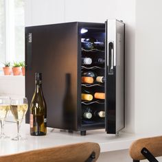 a wine cooler sitting on top of a counter next to two bottles of wine and glasses