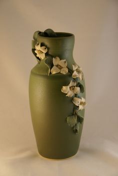 a green vase with white flowers on it