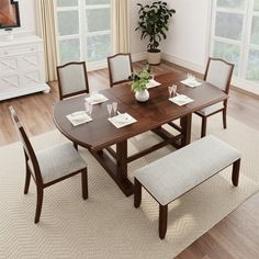 a dining room table with chairs and a bench in front of the window, next to a potted plant