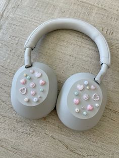 two gray headphones with pink and white hearts on them sitting on a wooden surface