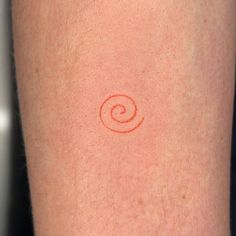 a close up of a person's arm with a small red tattoo on it