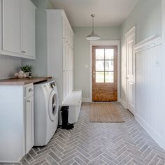 a washer and dryer are in the middle of a room with white cabinets