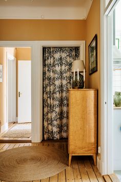 a living room with an area rug and wooden cabinet in the corner, along with pictures on the wall