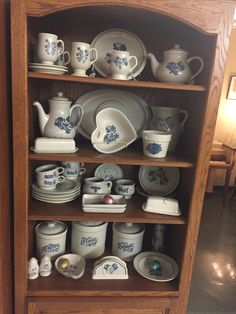 the china cabinet is full of blue and white dishes, cups, and saucers