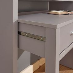 a desk with a book on top of it and a drawer underneath the desk is open