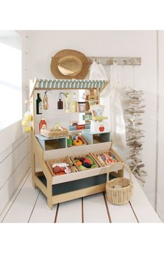 a toy kitchen is shown with food in the drawer and on the floor next to it