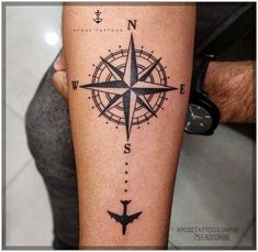 a man's arm with a compass tattoo on it and an airplane in the middle