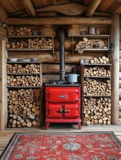 a red stove sitting in the middle of a room next to stacks of firewood