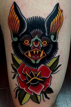 a tattoo on the leg of a person with a bat and roses in front of it