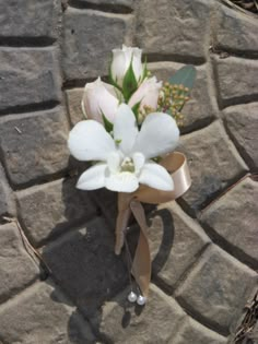 a boutonniere with white flowers and greenery on a cobblestone walkway