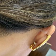 a close up of a person's ear with a gold ring on top of it