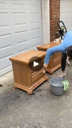 a woman bending over to pick up something from a trash can in front of a garage