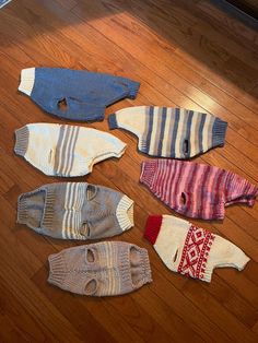 several knitted sweaters laid out on the floor