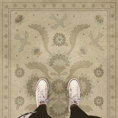 a person with white shoes standing in front of a rug