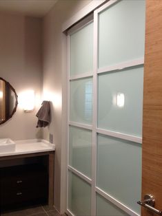 a bathroom with a sink, mirror and large sliding glass door to the shower area