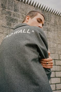 a man with his back turned to the camera, wearing a jacket that says wall