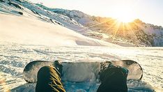 two snowboarders are sitting in the snow with their feet propped up against each other