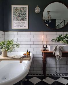 a bathroom with black and white tiles, a bathtub, mirror and candles on the wall