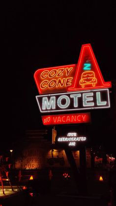 a motel sign lit up at night with the word cozy cone on it's side