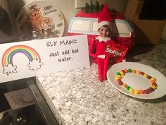 an elf is holding a candy bar near a sign that says elf magic just add hot water